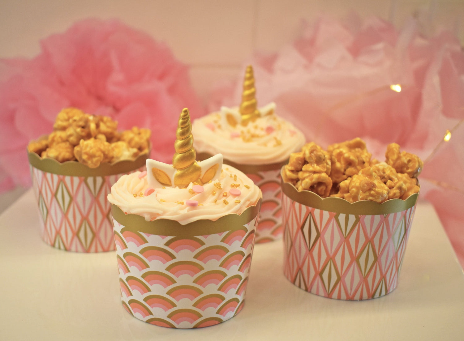 Stylish gold and pink baking cups and snack cups filled with caramel popcorn and unicorn cupcakes—perfect for parties, events, and dessert displays.